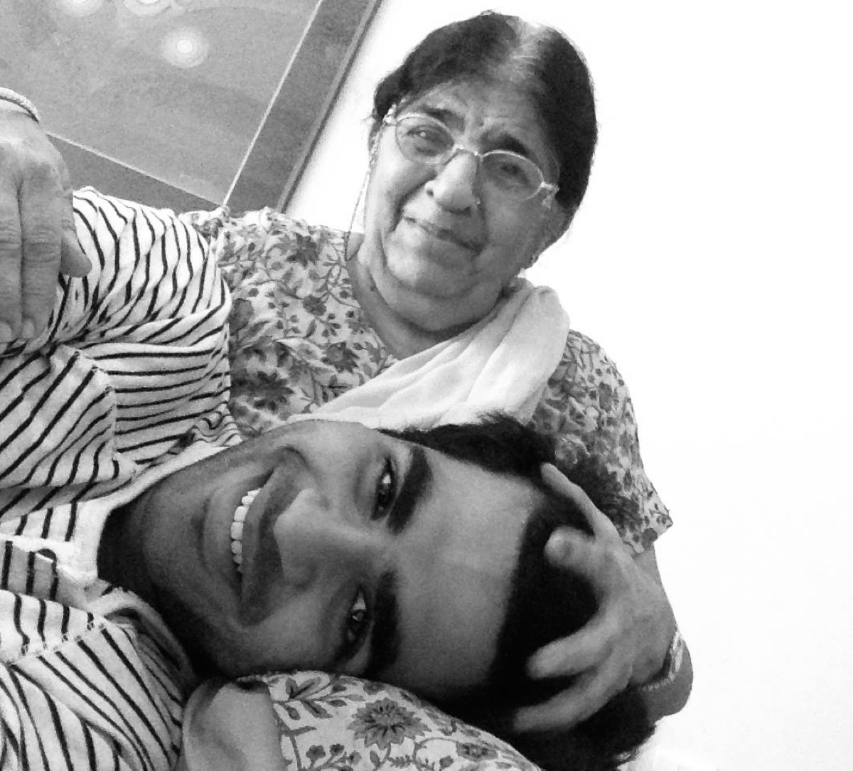 Black and white photograph of me resting against my grandmother, my dadi ma