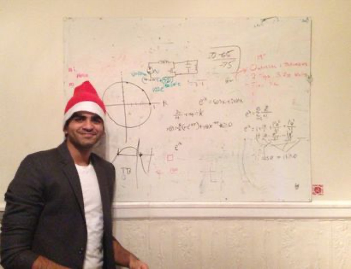 Standing next to a whiteboard covered in equations, wearing a Santa hat